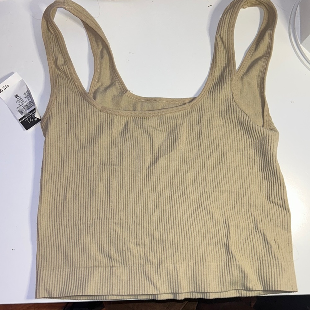 a beige/cream colored medium tank that is fitting and stretchy material